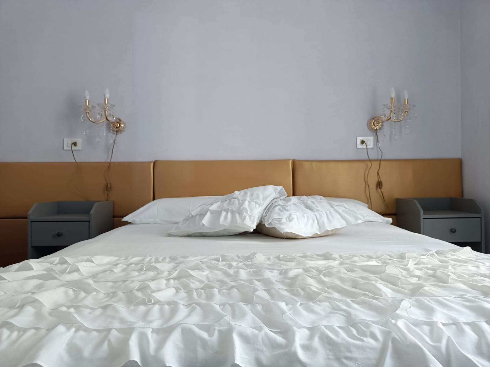 Camera da letto con testiera dorata e applique di cristallo